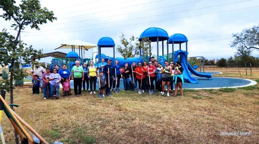 a group of people with shovels standing by playground equipment at a park in Ennis, Texas
