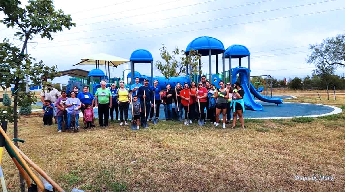 a group of people with shovels standing by playground equipment at a park in Ennis, Texas